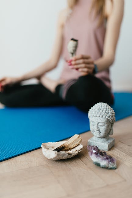 pexels-photo-4498360-4498360-1 Selective focus of crop faceless young female in casual wear meditating in lotus pose with white sage incense near Buddha head sculpture amethyst crystal and palo santo wood in stone bowl